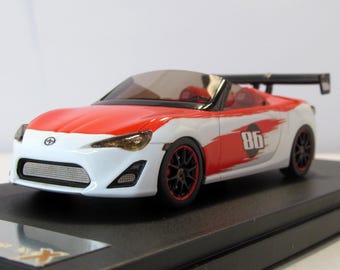 May include: A white and red toy car with a black spoiler and the number 86 on the side. The car is a convertible and has a black grill.