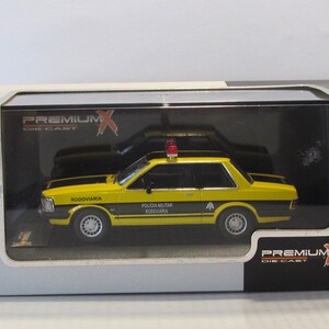 May include: A yellow and black diecast model car of a Brazilian police car. The car has a red light on top and the words "Policia Militar Rodoviaria" on the side. The car is in a clear plastic display case.