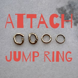 May include: Four gold jump rings, two with a more rustic finish and two with a smooth finish. The text "ATTACH JUMP RING" is written in red letters on a gray background.