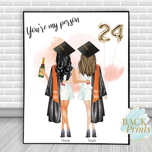 Pu&ograve; includere: Stampa di laurea con due donne in cappelli e toge, che tengono diplomi e una bottiglia di champagne. Il testo "You're my person" e "24" &egrave; visibile. I nomi delle donne "Annie" e "Taylor" sono in fondo alla stampa.