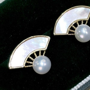 May include: A pair of gold earrings with a white mother-of-pearl fan design and a pearl drop.