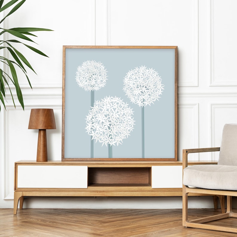 May include: A framed print of three white flower clusters on a light blue background. The flowers are stylized and resemble allium or globe thistle.