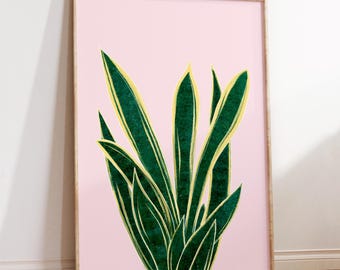 May include: A rectangular wall art print featuring a stylized illustration of a snake plant with dark green leaves and bright yellow edges, set against a solid light pink background, all enclosed within a thin, light-colored wooden frame.