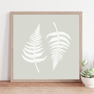 May include: A framed print with two white fern silhouettes on a light green background.