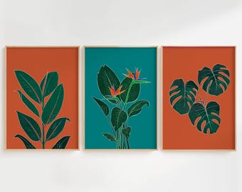 May include: A set of three framed wall art prints featuring botanical illustrations. The left and right prints show dark green foliage on a burnt orange background, while the center print displays bird of paradise flowers on a teal background.