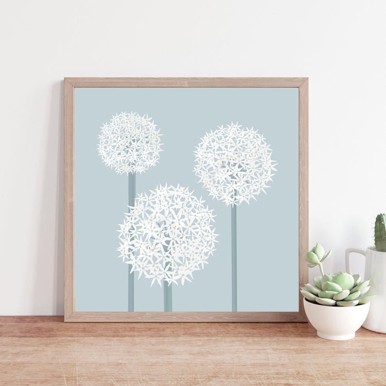 May include: A framed print of three white, round, flower-like plants on a light blue background. The plants have a starburst pattern.
