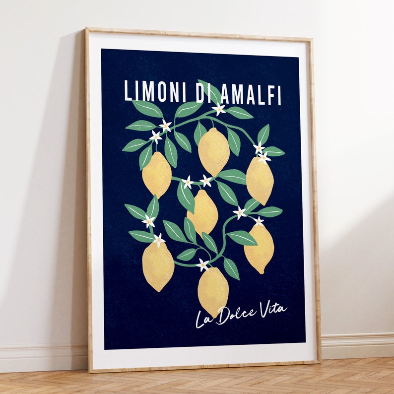 May include: A framed vertical wall art print featuring a deep navy blue background with a central illustration of yellow lemons on green leafy branches with small white flowers. The text LIMONI DI AMALFI appears at the top and La Dolce Vita at the bottom.
