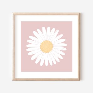 May include: A white daisy with a yellow center on a light pink background. The daisy is framed in a light wood frame.