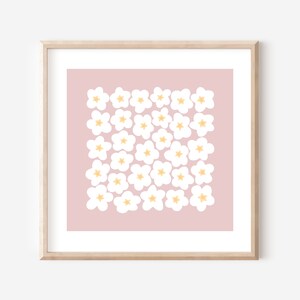 May include: A framed print with a pink background and a pattern of white flowers with yellow centers.