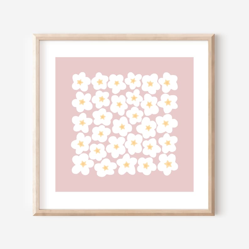 May include: A framed print with a pink background and a pattern of white flowers with yellow centers.