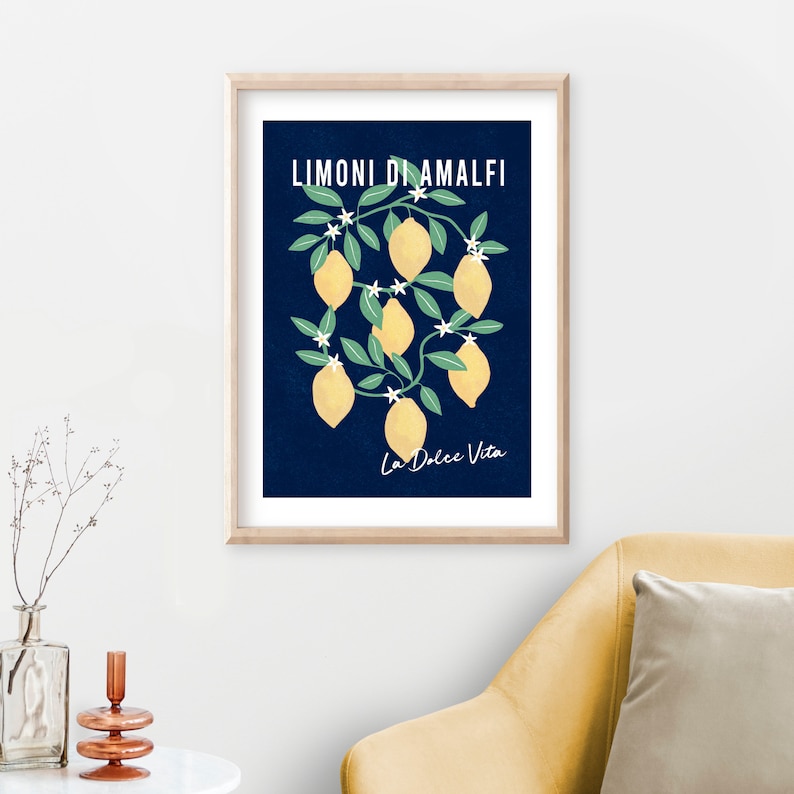 May include: A framed wall art print featuring a dark blue background with yellow lemons, green leaves, and white blossoms. The text LIMONI DI AMALFI is printed in white at the top, and the text La Dolce Vita is printed in white at the bottom.