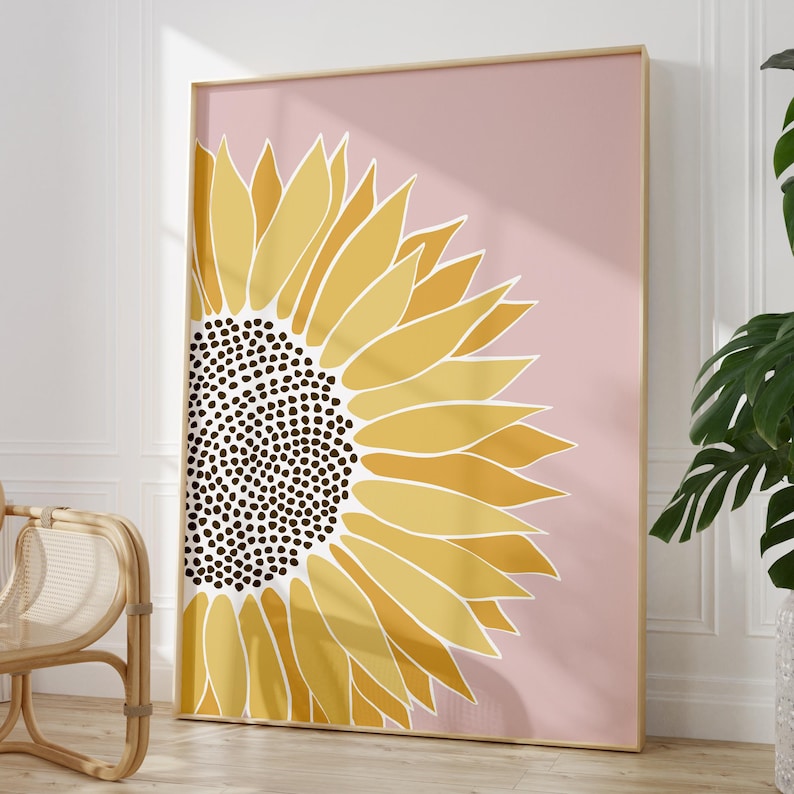 May include: A large, stylized sunflower with a yellow and brown center on a pink background. The sunflower is in a gold frame.