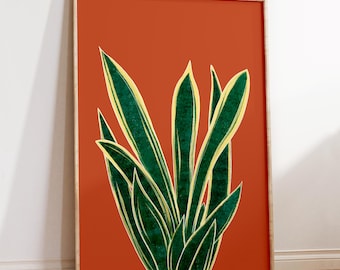 May include: A framed print of a stylized illustration of a green and yellow snake plant on a burnt orange background.