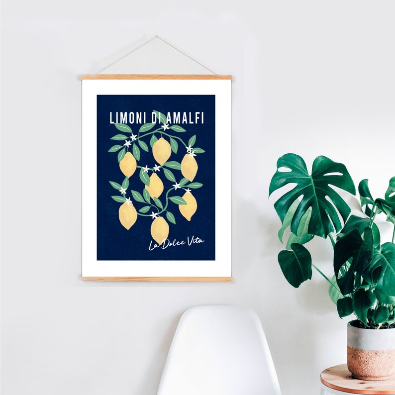 May include: A vertical wall hanging poster featuring a dark blue background with a central illustration of yellow lemons on green leafy branches with white flowers. The text LIMONI DI AMALFI and La Dolce Vita are printed in white on the poster.