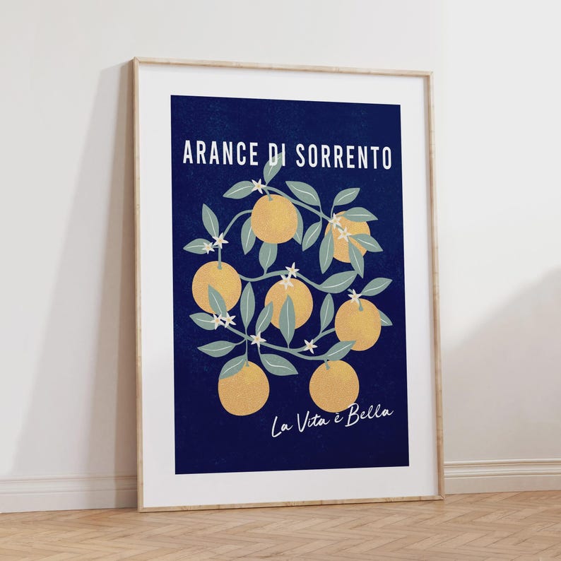 May include: A framed vertical art print featuring a deep navy blue background with a central illustration of orange branches bearing yellow oranges and small white blossoms. The text ARANCE DI SORRENTO and La Vita &egrave; Bella is printed in white.