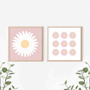 May include: Two framed prints with a pink background and white daisy illustrations. The first print features a single large daisy in the center. The second print features nine smaller daisies arranged in a grid pattern.