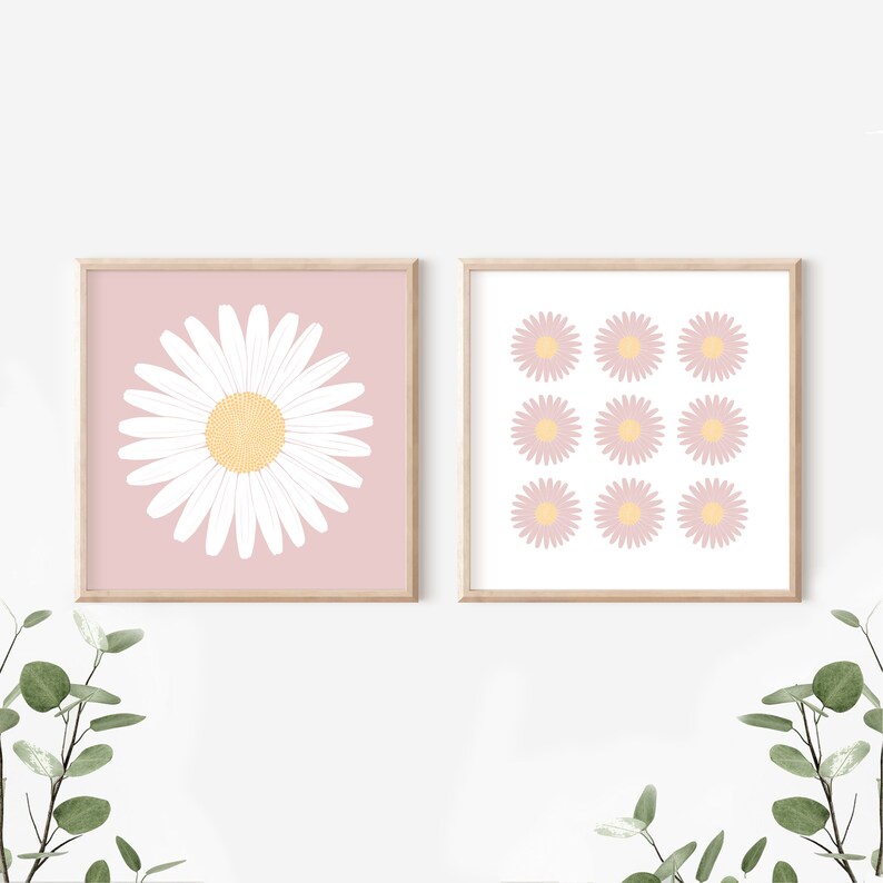 May include: Two framed prints with a pink background and white daisy illustrations. The first print features a single large daisy in the center. The second print features nine smaller daisies arranged in a grid pattern.