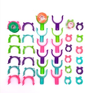 May include: Assortment of colorful plastic clips and rings. The clips are in various shapes, including U-shaped and circular. The rings are all circular and come in a variety of colors, including green, pink, purple, and blue.