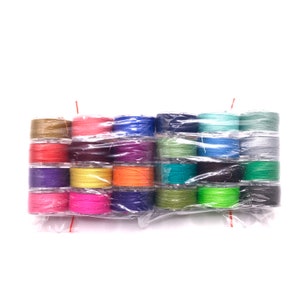 May include: A variety pack of 20 spools of thread in assorted colors, wrapped in clear plastic. The spools are arranged in two rows of ten, with the colors alternating.