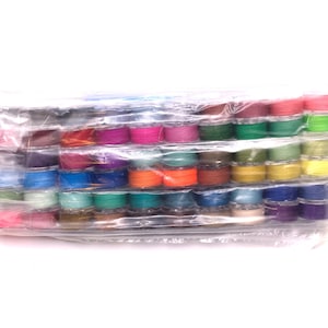 May include: A plastic package containing a variety of colorful thread spools. The spools are arranged in rows and are all the same size. The spools are wrapped in clear plastic and are ready to be used for sewing or crafting.