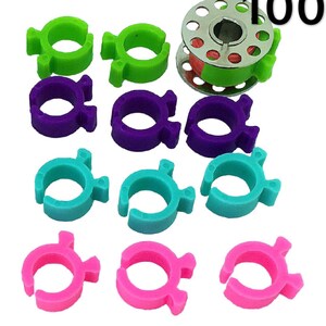 May include: A pack of 100 colorful plastic thread bobbin holders. The bobbin holders are in four colors: green, purple, blue, and pink. The bobbin holders are designed to fit standard sewing machine bobbins.