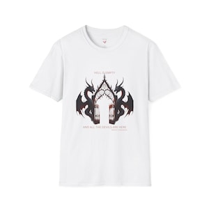 Puede incluir: Camiseta blanca con un diseño gótico. Dos dragones enmarcan una ilustración de puerta ornamentada. El texto "HELL IS EMPTY" y "AND ALL THE DEVILS ARE HERE" están impresos encima y debajo del gráfico.