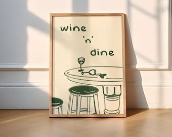 May include: A framed print with a white background and black line drawings of a table, two chairs, a glass of wine, and the text "wine 'n dine".