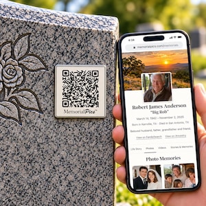 May include: A square metal plaque with a QR code and the text MemorialPics attached to a granite headstone with a carved rose. A smartphone displays a memorial webpage for Robert James Anderson with photos and biographical details.