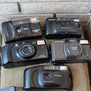 Puede incluir: Una taza de cerámica blanca con un asa negra y el texto "But First, Coffee" en negro y negrita. La taza está sobre una superficie blanca.