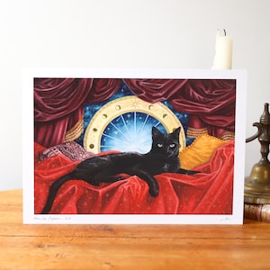 Puede incluir: Una impresión artística rectangular que muestra a un gato negro tumbado sobre una superficie de tela roja. Detrás del gato hay cortinas de color rojo intenso, un cojín amarillo y una ventana circular con un cielo azul estrellado y fases lunares.