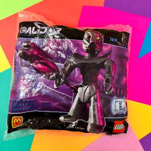 May include: A plastic bag containing a LEGO Galidor Gorm action figure. The figure is black and silver with a purple weapon. The bag has the words "Galidor Defenders of the Outer Realm" and "Gorm" printed on it. The figure is number 3 in the series.