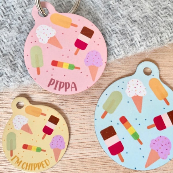 May include: Three colorful pet tags with ice cream and popsicle designs. One pink tag says "Pippa". Another yellow tag says "I'm Chipped". The third tag is light blue. All tags have a metal ring for attachment.