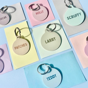 Può includere: Assortimento di targhette rotonde per animali domestici di diversi colori con nomi stampati, tra cui "Oscar", "Molly", "Scruffy", "Patches", "Larry", "Teddy".