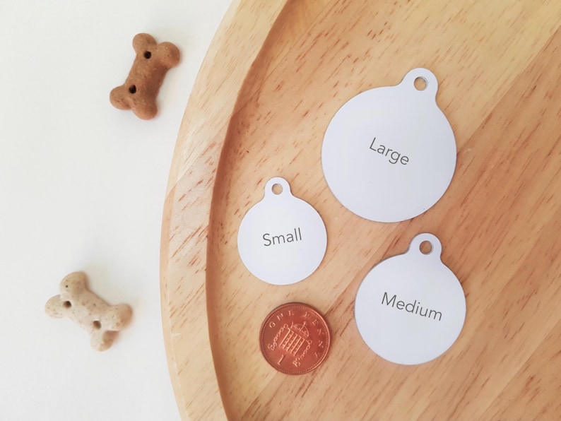 Pu&ograve; includere: Un vassoio di legno contiene tre targhette bianche e rotonde per animali domestici con le scritte "Large", "Small" e "Medium". Sono presenti anche due biscotti per cani a forma di osso e una moneta da un penny. Le targhette hanno un foro per l'attacco.