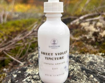 Puede incluir: Un frasco cuentagotas de vidrio blanco que contiene tintura de violeta dulce, etiquetado con el logotipo de Kingdom Remedies, el nombre botánico violata odorata y un volumen de 59 ml. El frasco tiene un tapón cuentagotas blanco.