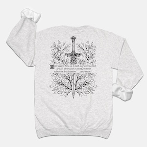 May include: A grey long-sleeve sweatshirt with a black and white illustration of a sword surrounded by floral designs. The text "once upon a time, in a land long since burned to ash, there lived a young princess who loved her kingdom... very much." is printed on the sweatshirt.