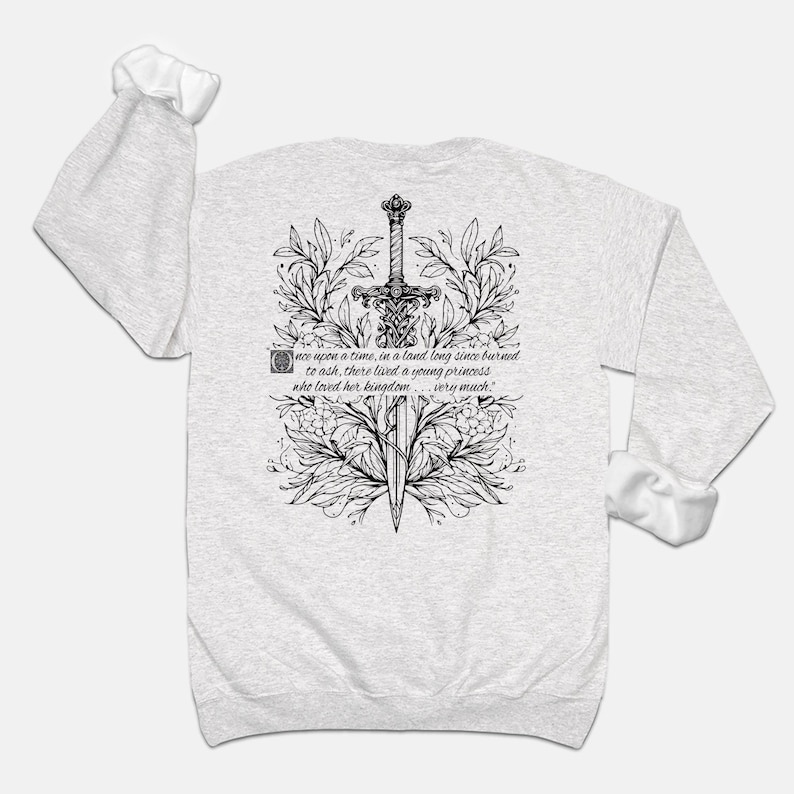 May include: A grey long-sleeve sweatshirt with a black and white illustration of a sword surrounded by floral designs. The text "once upon a time, in a land long since burned to ash, there lived a young princess who loved her kingdom... very much." is printed on the sweatshirt.