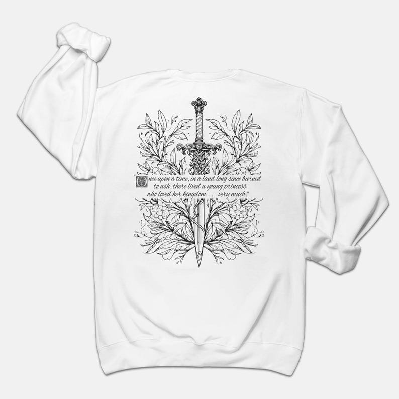 May include: White long-sleeve sweatshirt with a black and white illustration of a sword surrounded by floral designs. The text "once upon a time, in a land long since burned to ash, there lived a young princess who loved her kingdom... very much." is printed below the illustration.