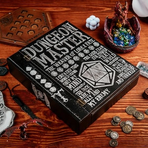 May include: A black wooden Dungeon Master box with white text and dice graphics. The box is surrounded by game-related items, including coins, a dragon figurine, and a wooden game board. The text on the box reads "Dungeon Master".