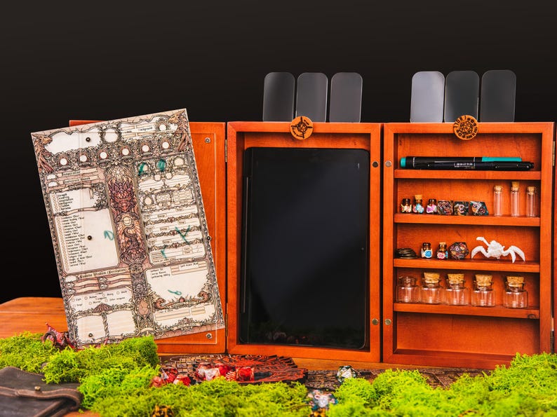 May include: A wooden tabletop gaming organizer featuring a hinged design with a character sheet display on the left, a central tablet slot, and a right-side shelving unit containing small glass vials, dice, a pen, and a white creature figurine.