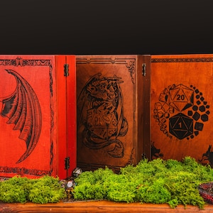 May include: Three rectangular wooden boxes with hinged lids. The left box is bright red with a black dragon wing engraving. The center box is brown with a dragon and die engraving. The right box is brown with a circular pattern of dice.