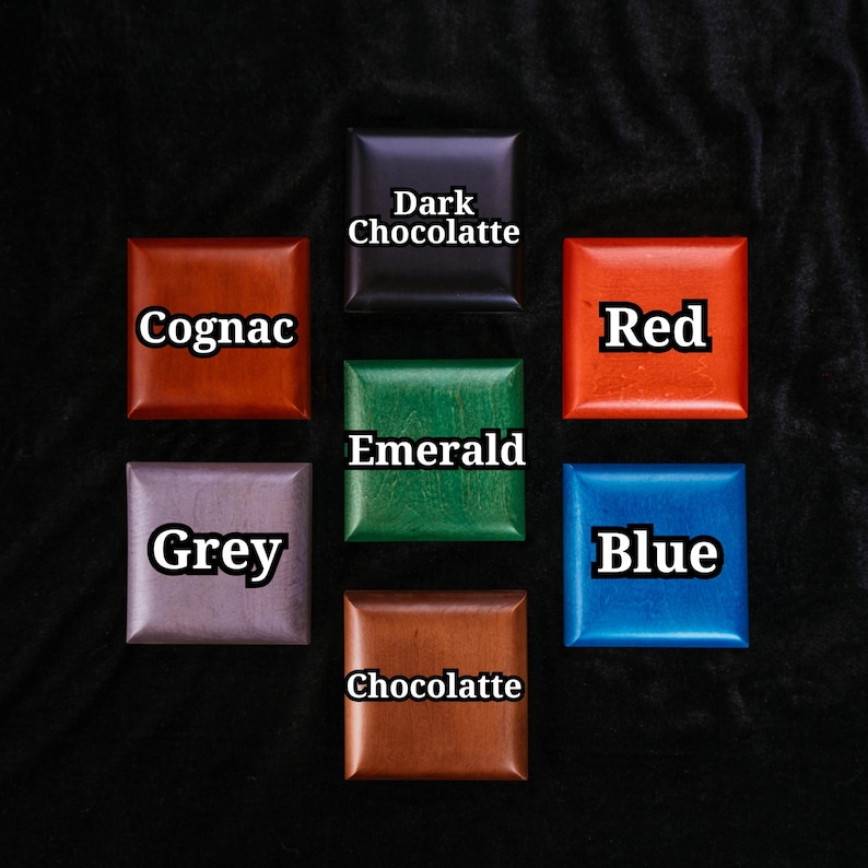 May include: Seven square wooden blocks arranged in a grid, each labelled with a colour name: Dark Chocolatte, Cognac, Red, Emerald, Grey, Blue, and Chocolatte. The blocks feature smooth, polished surfaces in distinct shades of brown, red, green, grey, and blue.