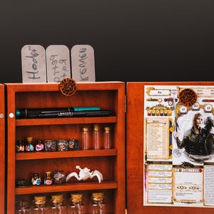 May include: A wooden cabinet with shelves filled with small glass bottles, vials, and decorative items. The cabinet has a dark stain and is open, revealing the contents. The cabinet also has a printed character sheet and labels with the names "Hodor", "betty", and "Kemen".