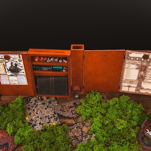 Peut inclure: Un ensemble de jeu de r&ocirc;le de table en bois avec une finition marron. L'ensemble comprend un compartiment de rangement pour d&eacute;s, un portefeuille en simili cuir et divers accessoires de jeu. Un paysage de mousse verte et des cartes de jeu sont au premier plan.