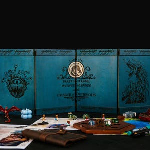 May include: A teal-colored, four-panel game master screen with illustrations and text, including "I am the Keeper of Lore, Weaver of Fates, and Chaser of Dungeons." Various game pieces, dice, and a leather-bound notebook are arranged in front.