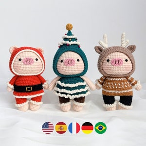 Puede incluir: Tres peluches de cerdo de crochet vestidos con atuendos navideños. Uno lleva un traje de Papá Noel rojo, otro lleva un disfraz de árbol de Navidad verde y el tercero lleva un disfraz de reno marrón.
