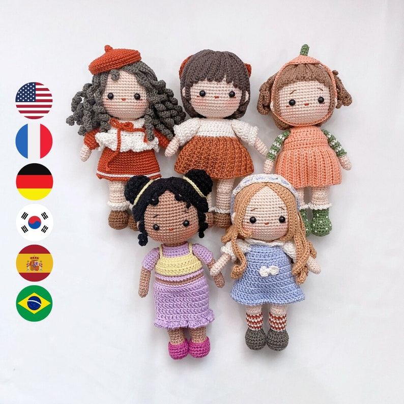 May include: Five crocheted dolls with different colored dresses and hair. The dolls are all wearing different colored dresses and have different colored hair. The dolls are all smiling and have big eyes.