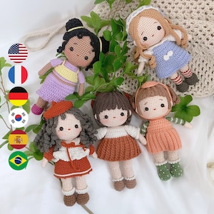 May include: Five crocheted dolls with different colored dresses and hair. The dolls are all wearing different outfits, including a purple dress, a brown dress, a pink dress, a blue dress, and a red dress. The dolls are all smiling and have different hair colors.