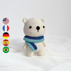 May include: White crocheted polar bear wearing a blue and teal striped scarf. The bear has black eyes and a black nose.