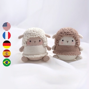 May include: Two crocheted sheep plushies, one white and one brown, with embroidered eyes and mouths. The sheep are sitting on a white surface.